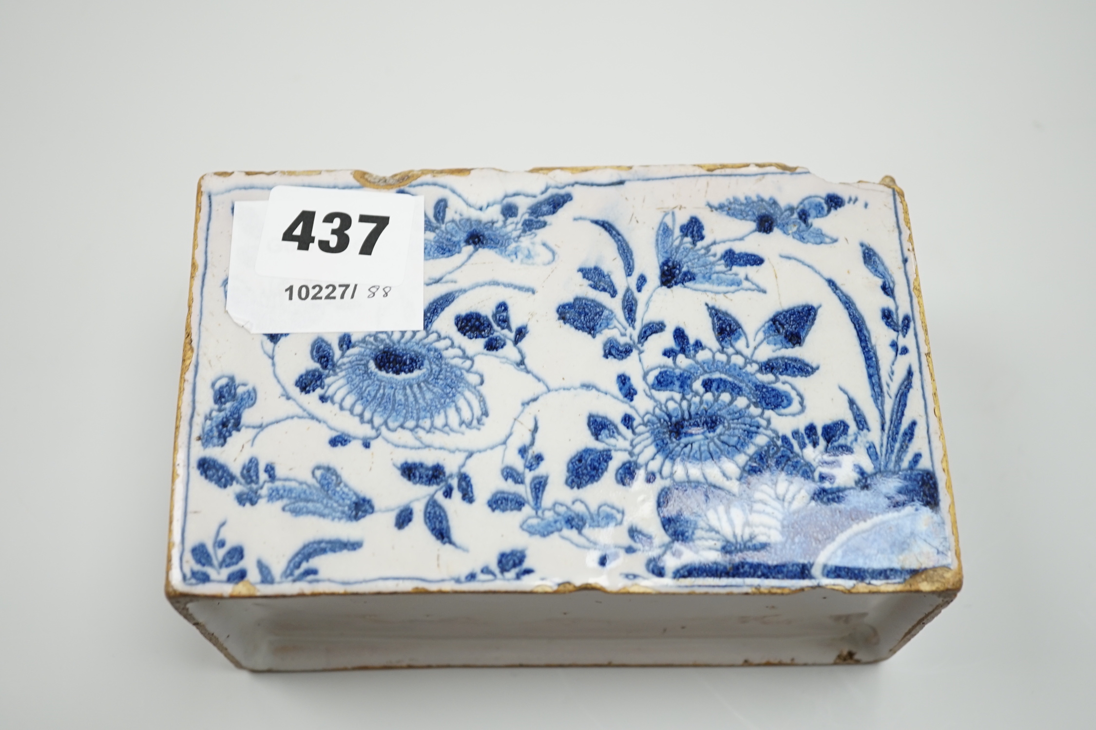 A mid 18th century English delftware flower brick, probably Lambeth, painted in underglaze blue with stylised chrysanthemums, 15cm wide